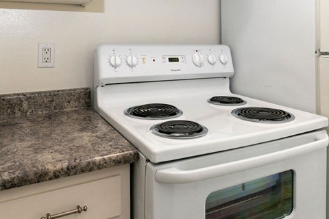 A white stove with four burners is in a kitchen.