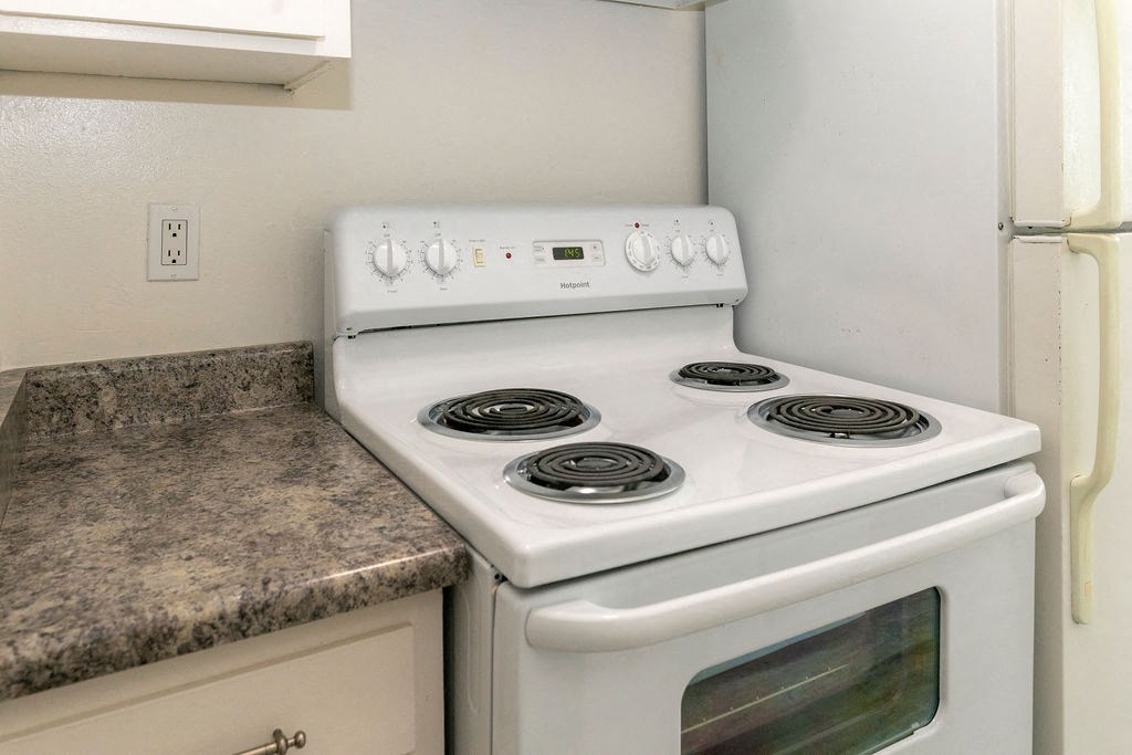a white stove top oven in a kitchen next to a refrigerator