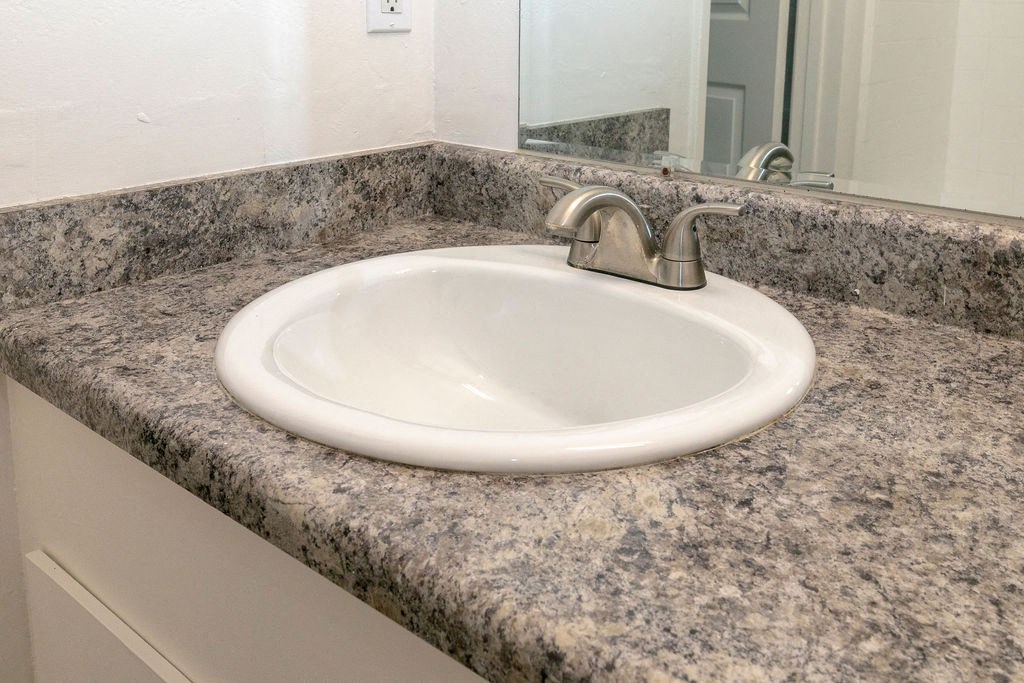 a bathroom sink with granite counter top and a mirror