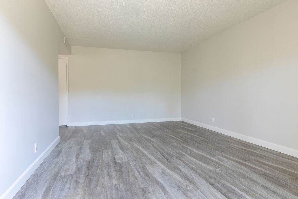 an empty room with vinyl flooring and white walls