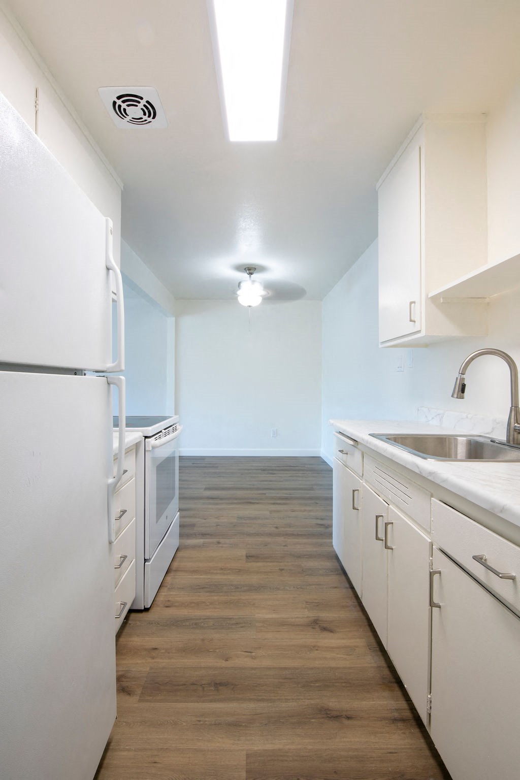 a kitchen with white cabinets and a sink and a refrigerator