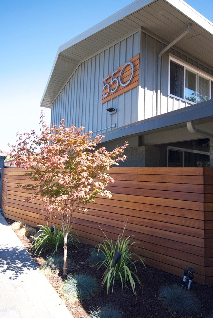 a house with a wooden fence and a tree in front of it