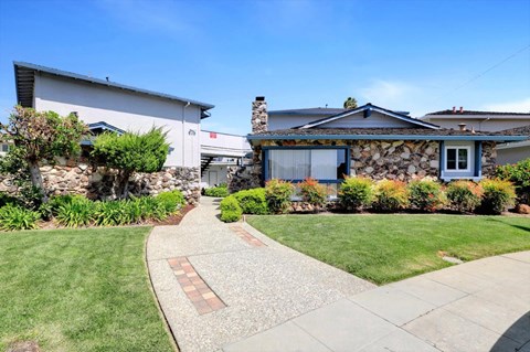 A house with a stone wall and a grey roof.