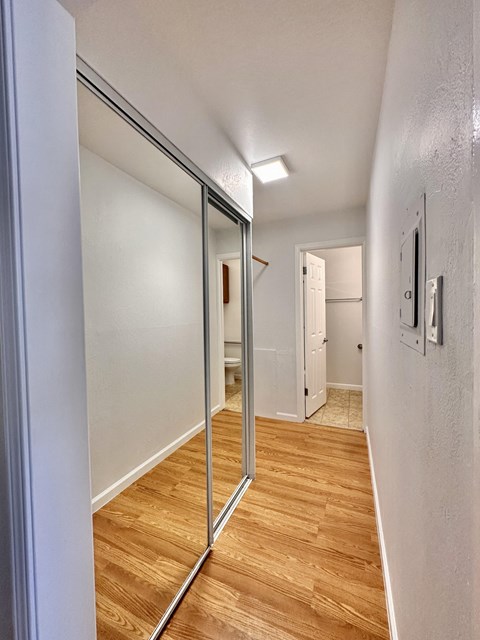 a hallway with a mirror and a door to a bedroom