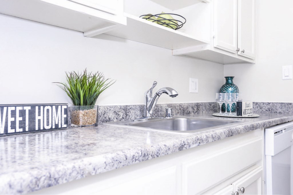 a white kitchen with a sink and a sign that says sweet home