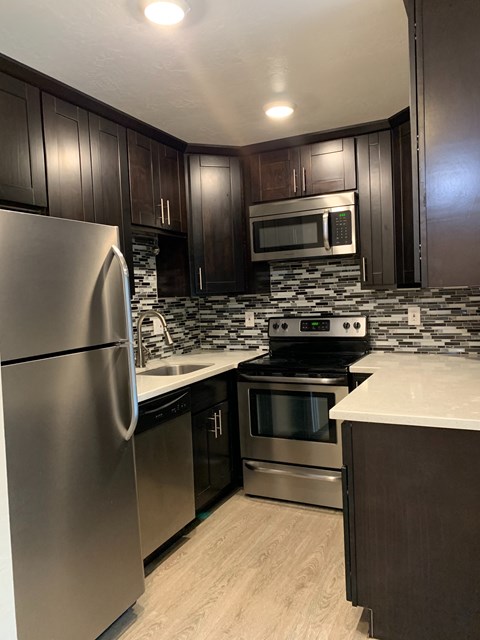 A modern kitchen with dark wood cabinets and stainless steel appliances.