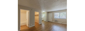 an empty living room with a hard wood floor and a door to a closet