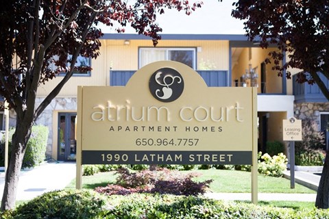 A sign for Atrium Court Apartment Homes stands in front of a building.