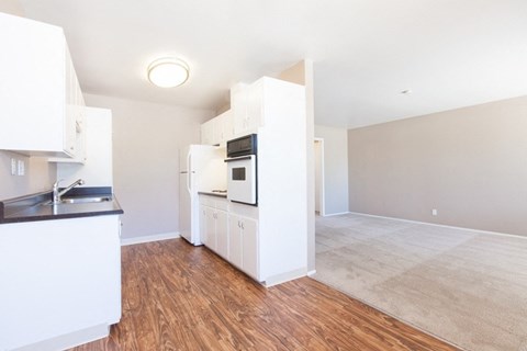 A kitchen with white cabinets and a wooden floor.