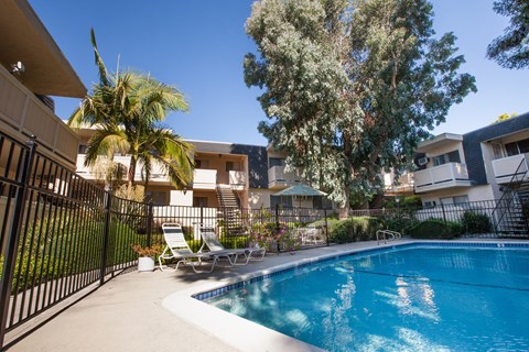 A pool surrounded by a black fence and chairs.