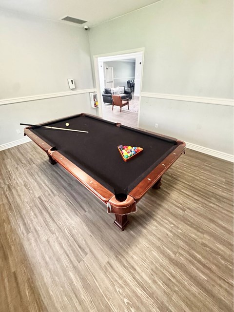 A pool table in a room with light wood flooring.