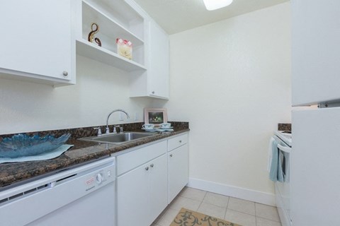 A small kitchen with white cabinets and a granite countertop.