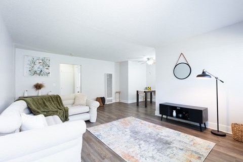 A white couch with a green throw is in a living room with a rug and a black speaker.