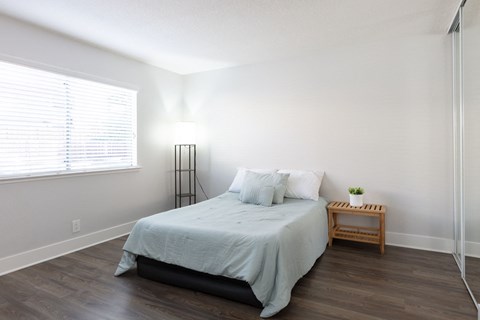 A bedroom with a bed, nightstand, and window.
