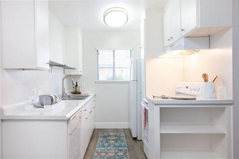A small white kitchen with a sink and a refrigerator.