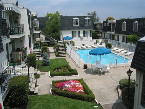 A pool surrounded by a patio and a small garden.