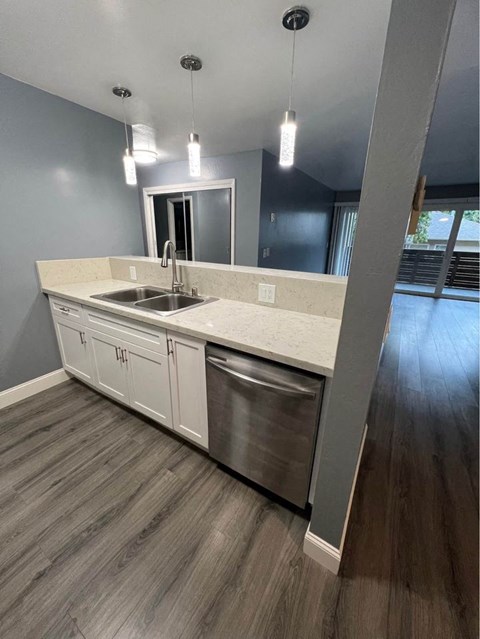 A modern kitchen with a stainless steel dishwasher and white countertops.