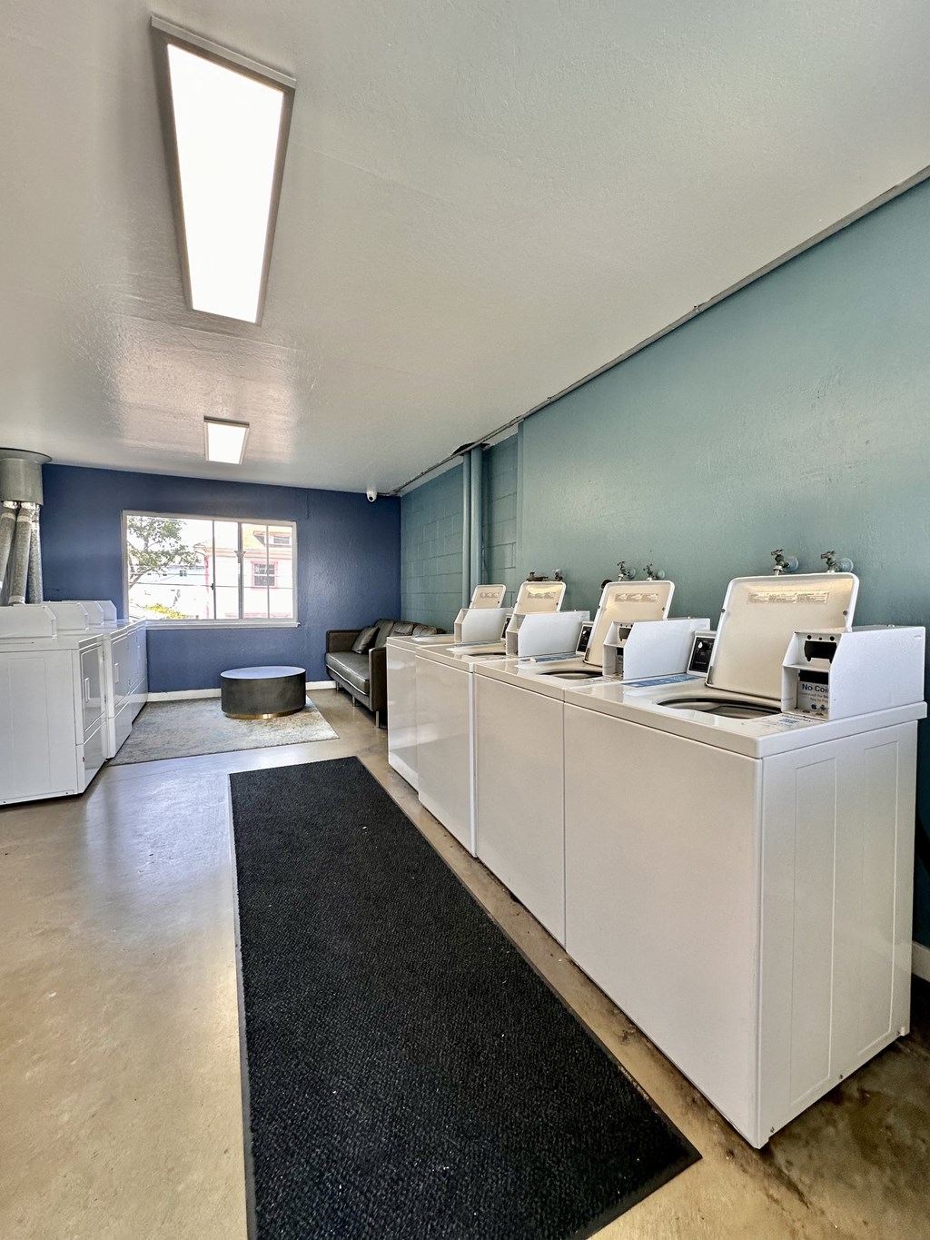 a laundry room with white machines and a black rug at The Chase Apartment Homes, California