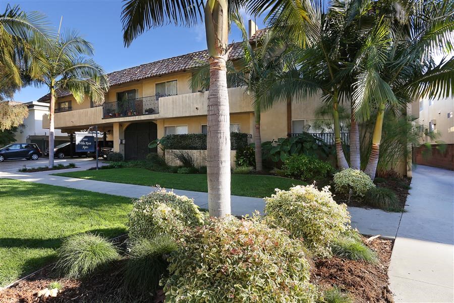 a house with palm trees and a sidewalk