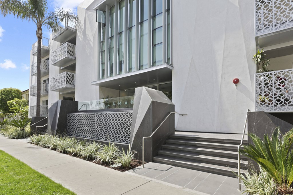 a large white building with stairs and a sidewalk in front of it