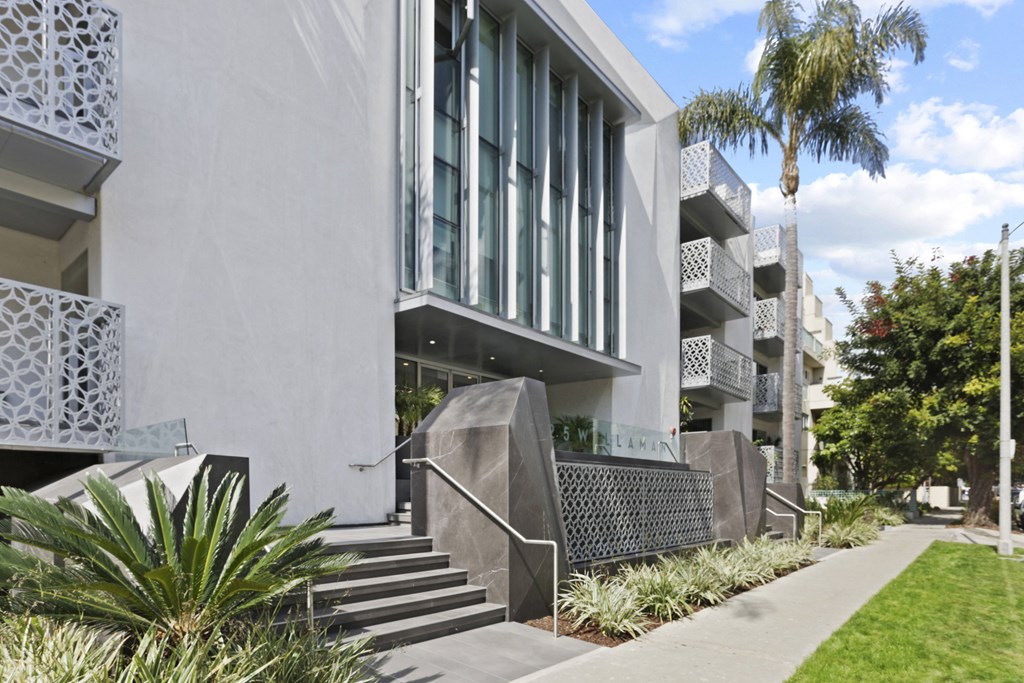 the exterior of a building with stairs and palm trees