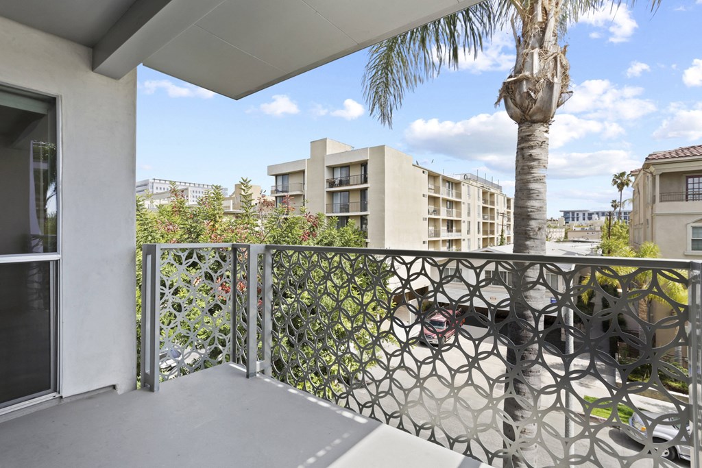 a balcony with a view of a palm tree and apartment buildings