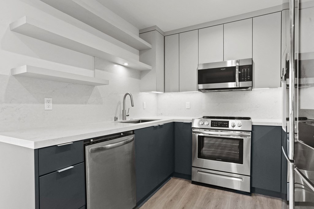 a kitchen with black and white cabinets and stainless steel appliances
