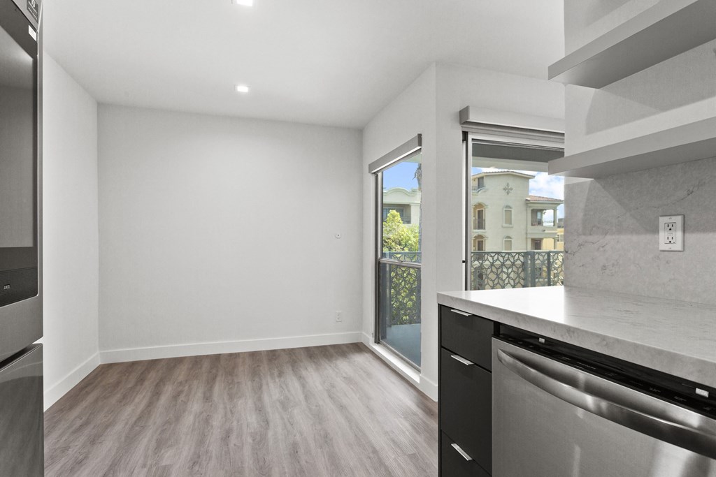 an empty kitchen and living room with a door to a balcony