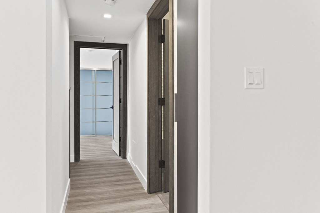 a hallway with wood floors and white walls and black doors