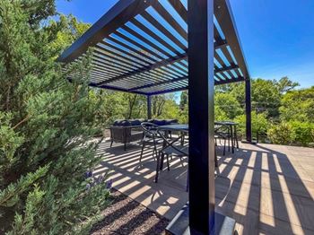 A patio with a table and chairs under a blue and white striped awning.