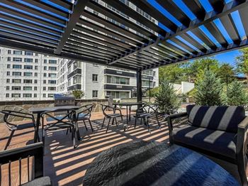 A patio with a striped couch and a table with chairs.