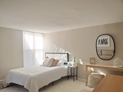 A bedroom with a large bed and a round mirror on the wall.