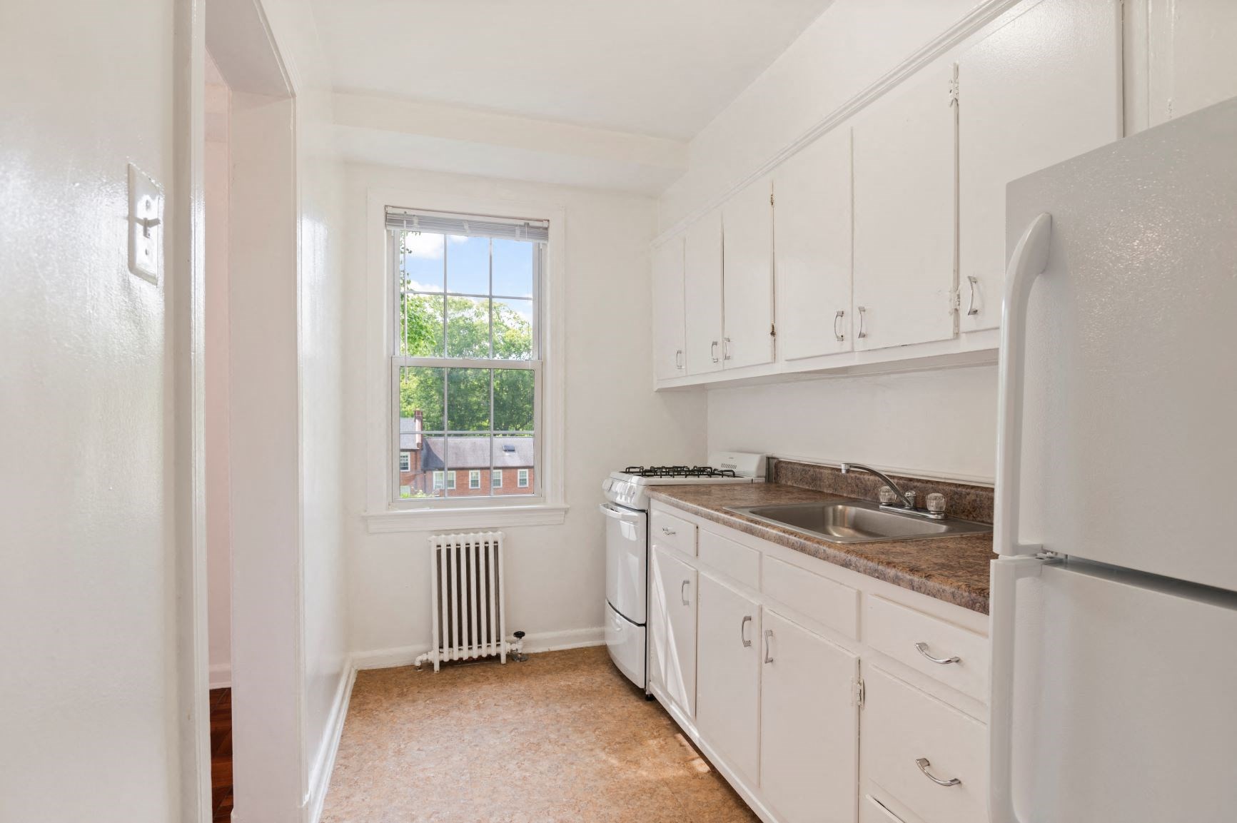 a kitchen with white cabinets and a window