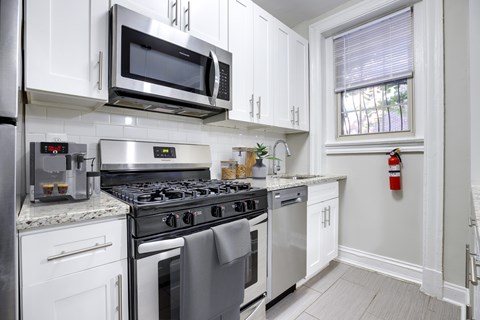 A modern kitchen with a stainless steel oven and white cabinets.