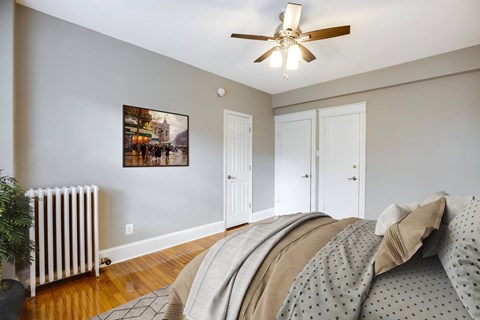 A bedroom with a bed, a ceiling fan, and a picture on the wall.