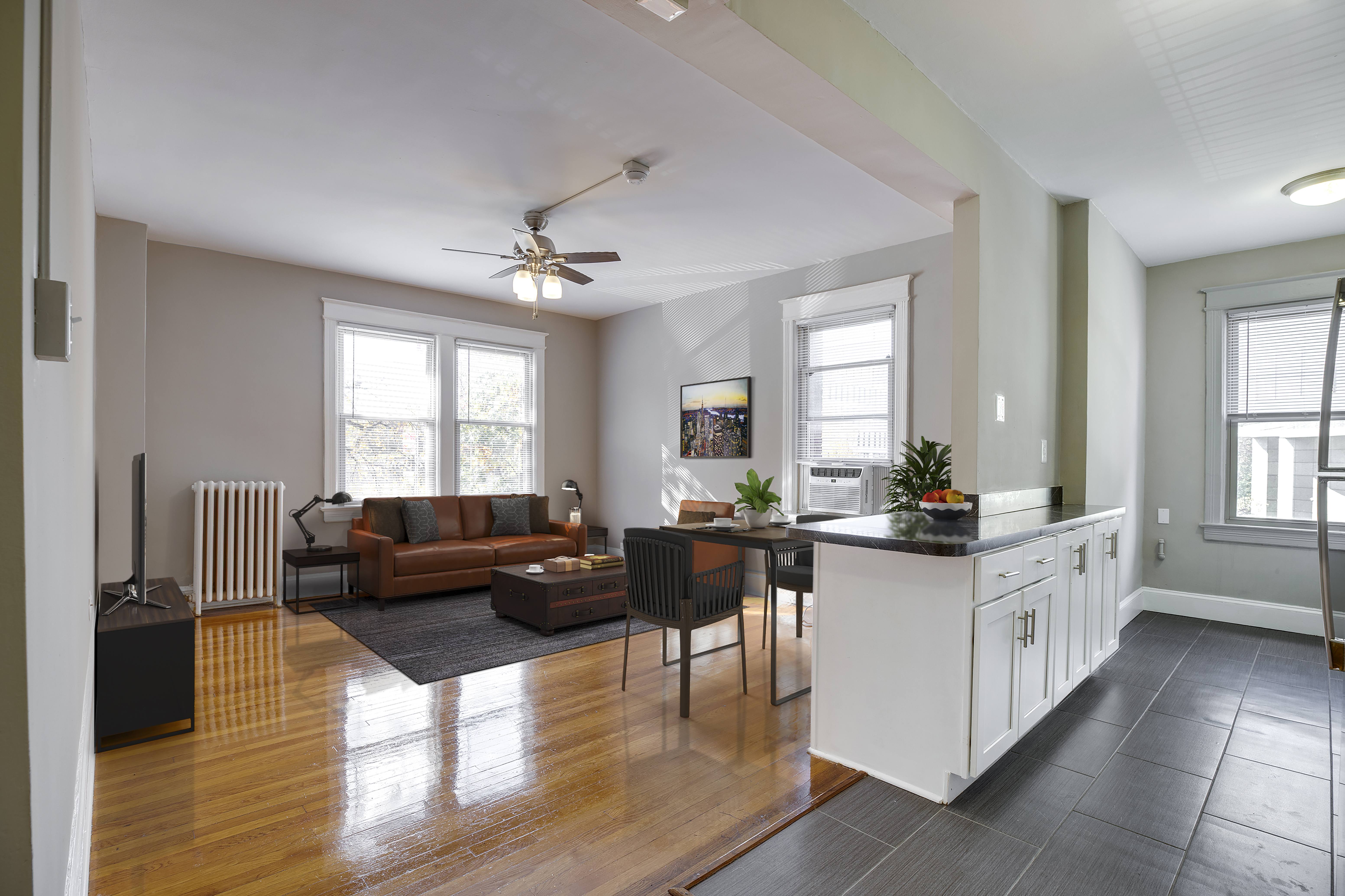 A living room with a brown couch and a wooden floor.