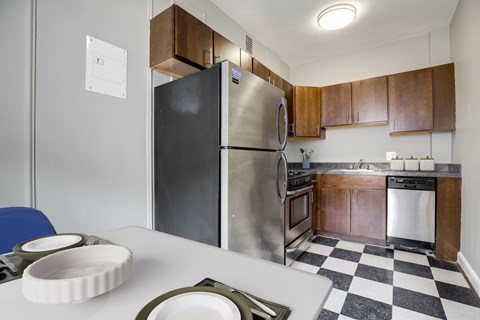 A black and white checkered floor in a kitchen with a stainless steel refrigerator.