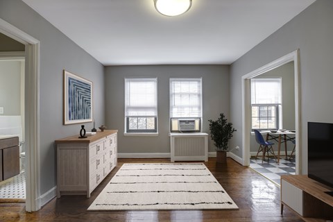A living room with a rug on the floor and a television on the right side.