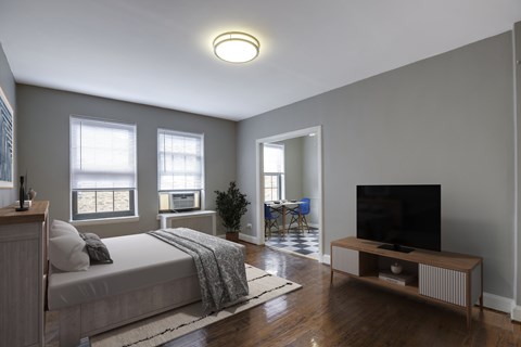 A bedroom with a bed, a television, and a chair.