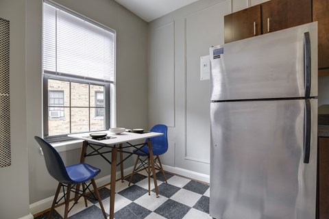 A kitchen with a table and chairs and a refrigerator.