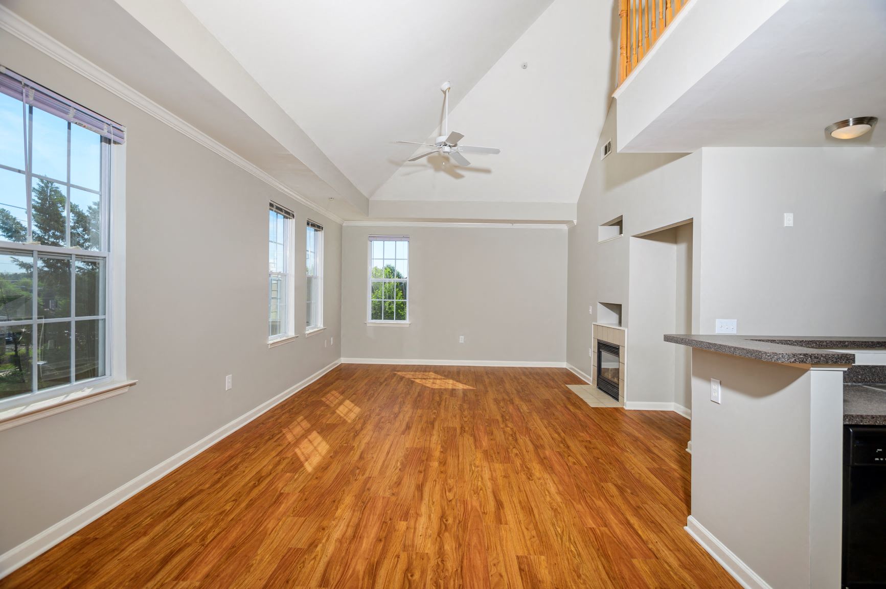 an empty living room with wood floors and a ceiling fan