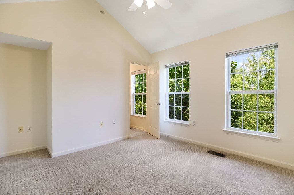 an empty living room with two windows and a door
