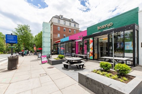 A street view of a shopping area with a Frozayo store in the foreground.