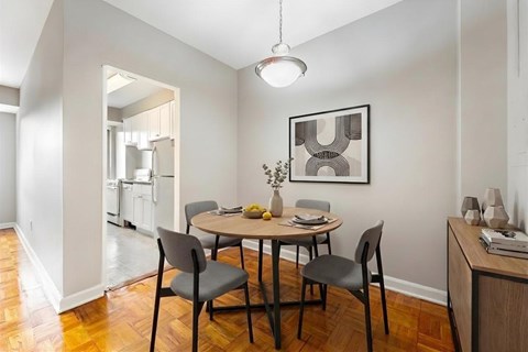 A dining room with a table set for two and a framed picture on the wall.