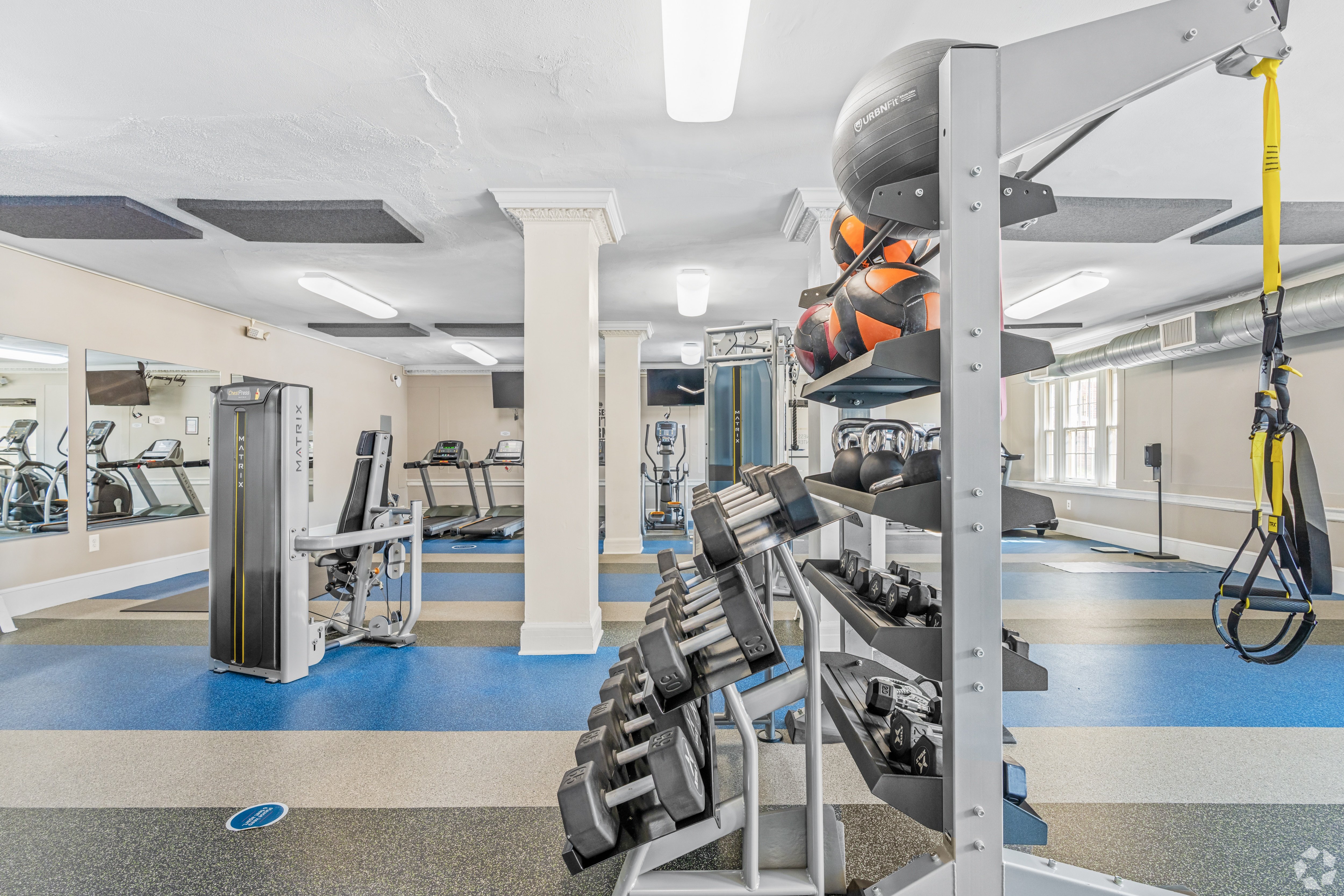 A gym with a variety of equipment including free weights, medicine balls, and strength machines at Kew Gardens in Georgetown, Washington DC 20007