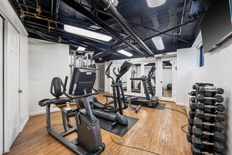 a gym with treadmills and other exercise equipment on a wooden floor