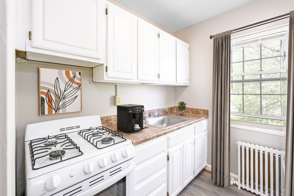A white kitchen with a white stove and white cabinets.