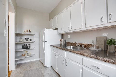 A kitchen with white cabinets and a granite countertop.