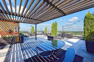 an outdoor patio with a blue table and chairs and a view of the city - Photo Gallery 2