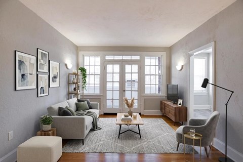 A living room with a grey couch, a coffee table, a chair, a television, and a plant.